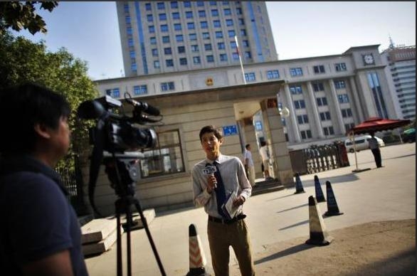 Một phóng viên cùng ekip truyền hình đang thực hiện một bản tin trước phiên xét xử cựu Bí thư Thành ủy Trùng Khánh Bạc Hi Lai bên ngoài trụ sở Tòa án Nhân dân Trung cấp Tế Nam, tỉnh Sơn Đông