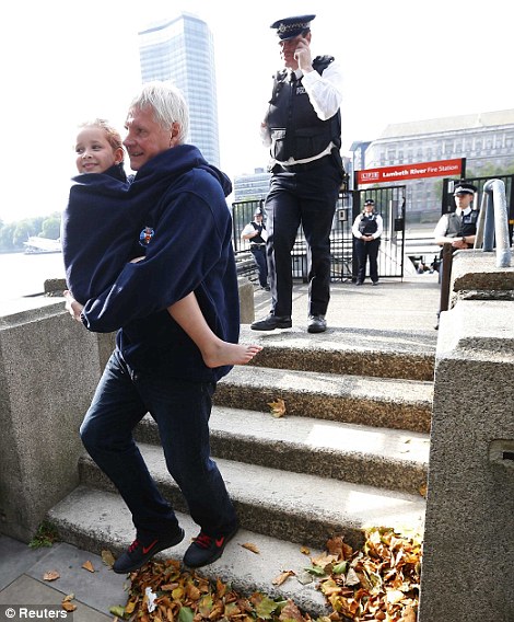 A man carries a child rescued from the Thames after an amphibious tourist vehicle caught fire 