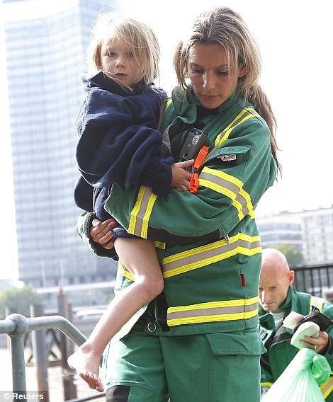 A member of the London Ambulance Service holds a child rescued from the Thames after an amphibious tourist vehicle caught fire as it travelled down the river