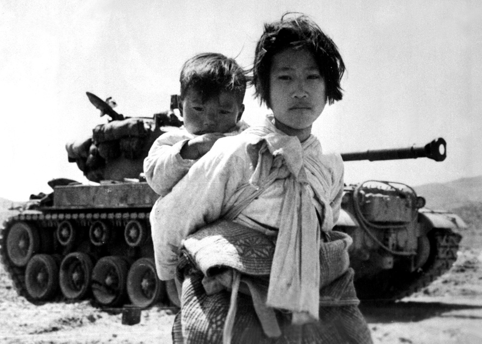  	Ngày 9/6/1951, người chị Triều Tiên cõng trên lưng là đứa em nhỏ bé của mình mà đằng sau là chiếc xe tăng hạng nặng.