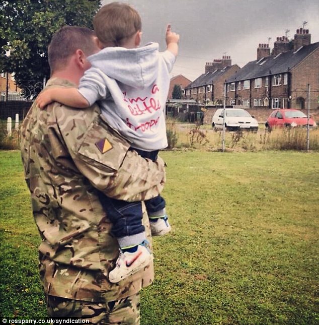 Pointing: Harley Kincaid, in a 'Little Trooper' hoodie, sitting in the arms of his father