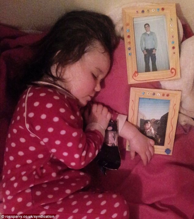 Please come home: Lailah Pagdin, aged two and a half, cuddles up with pictures of her father