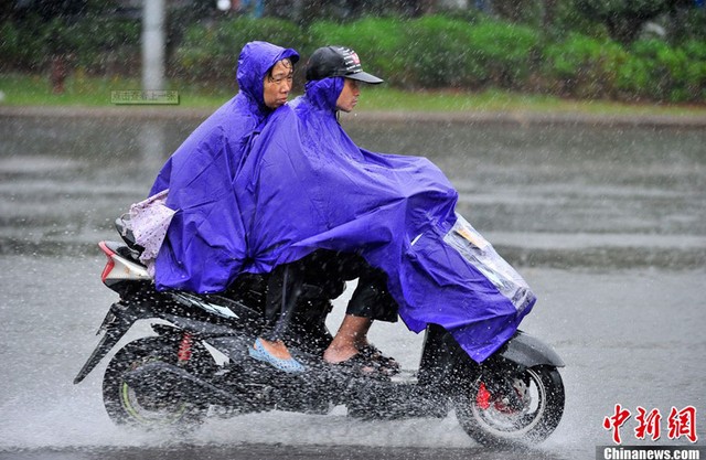 
	Hai người dân đảo Hải Nam cố gắng giữ áo mưa khỏi bị gió tốc.