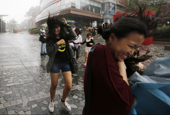 Khách du lịch chống chọi với gió lớn tại Hong Kong, khi siêu bão Utor đang đổ bộ vào miền đông nam Trung Quốc.