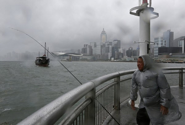 Một người đàn ông đứng trước gió bão lớn tại cảng Victoria, Hong Kong.