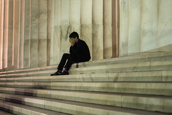 	Một người đàn ông ngồi trước Đài tưởng niệm Lincoln ở Washington D.C.