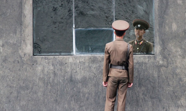 Một binh sĩ Triều Tiên đứng trước cửa sổ kính trên tường dọc bờ sông Yalu gần thị trấn Sinuiju.
