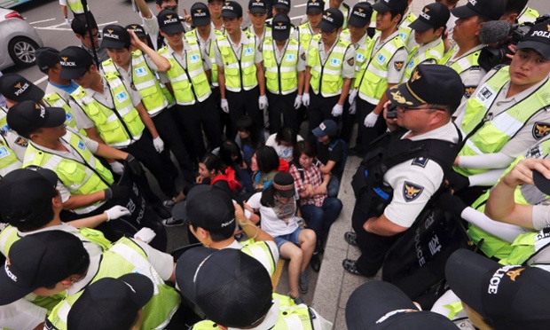 Cảnh sát đứng vây quanh một nhóm biểu tình bị bắt giữ ở Seoul, Hàn Quốc.
