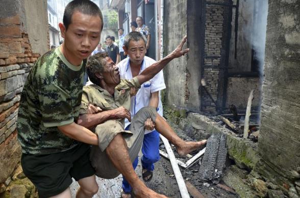 Ông Li Rong, 61 tuổi, được các nhân viên cứu hộ đưa khỏi ngôi nhà của ông bị lửa thiêu rụi tại thành phố Ôn Lĩnh thuộc tỉnh Chiết Giang, Trung Quốc.