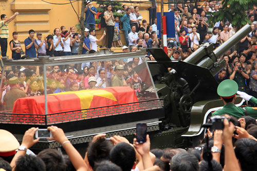 Xe quân sự chở linh cữu phủ quốc kỳ của Đại tướng Võ Nguyên Giáp đi qua đường phố với hàng nghìn người đứng hai bên vỉa hè vẫy chào và cầu nguyện cho Đại tướng ở Hà Nội, Bức ảnh được ghi lại bởi phóng viên của hãng tin AP.