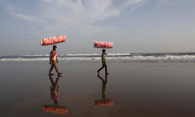Các cậu bé bán kẹo đi trên bờ biển ở Puri, Ấn Độ.