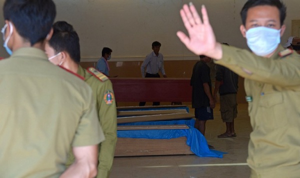 	Cảnh sát Lào gác bên cạnh quan tài chứa thi hài những hành khách xấu số đầu tiên được vớt lên từ chiếc máy bay gặp nạn