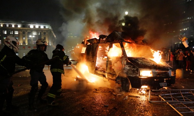 Lính cứu hỏa cố gắng dập tắt một chiếc ô tô bị cháy sau khi bị đốt bởi những người biểu tỉnh ở Sao Paulo, Brazil