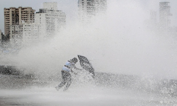 Một người đàn ông cố gắng lấy ô để che khỏi ướt, khi một con sóng mạnh vỗ vào bờ biển ở Mumbai, Ấn Độ.