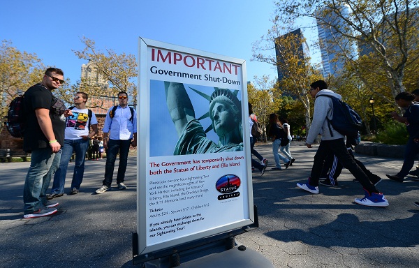 	Du khách Mỹ đứng trước tấm biển thông báo rằng Tượng Nữ thần Tự do đã bị đóng cửa tham quan do chính phủ Mỹ đóng cửa.