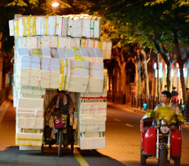 Người phụ nữ nhọc nhằn đạp xe ba bánh chở các thùng xốp trên đường phố đêm ở Nam Kinh, Trung Quốc.