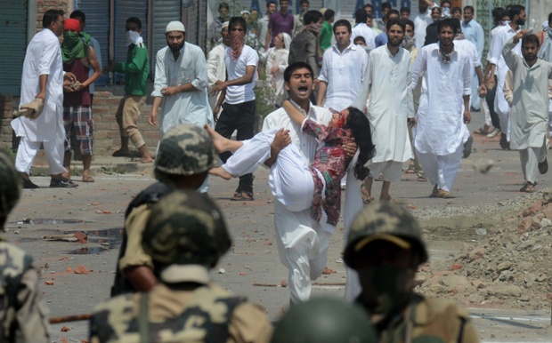 Nam thanh niên bế một phụ nữ bị thương trong cuộc đụng độ giữa những người biểu tình và cảnh sát chống bạo động ở Srinagar, Ấn Độ.