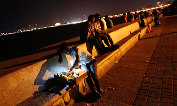 Một người bán dạo đồ ăn nhanh kiểm tra hàng của mình tại một khu vực di dạo bên bờ biển ở Mumbai, Ấn Độ.