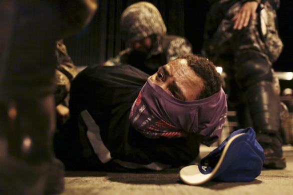 Một người đàn ông bịt mặt bị cảnh sát bắt giữ khi tham gia biểu tình tại thành phố Belo Horizonte, Brazil.
