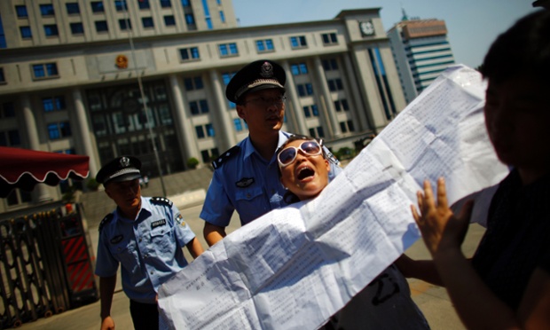 Cảnh sát cưỡng chế một người biểu tình khỏi khu vực trước tòa án nhân dân Tế Nam, Trung Quốc, nơi sẽ xét xử vụ án Bạc Hy Lai vào ngày hôm nay.