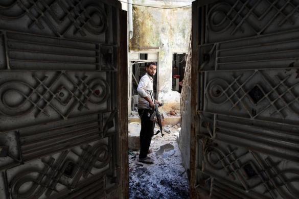 Một chiến binh thuộc lực lượng quân đội Syria tự do cầm vũ khí trong một căn nhà đổ nát tại thành phố Aleppo, Syria.