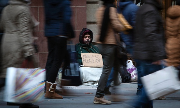 Một người ăn xin đeo ngồi cạnh Đại lộ số 5 khi người mua sắm đi qua ở New York, Mỹ.