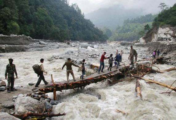 Các binh sĩ giúp đỡ người dân đi qua cây cầu tạm tại vùng lũ lụt ở Uttarakhand, Ấn Độ.