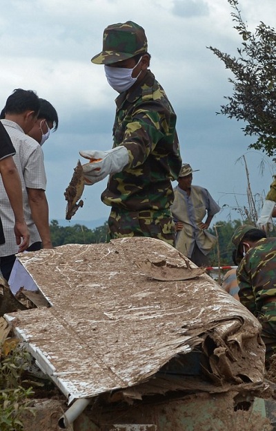 	Một người lính Lào thu gom mảnh vỡ của chiếc máy bay gặp nạn (Ảnh AFP)