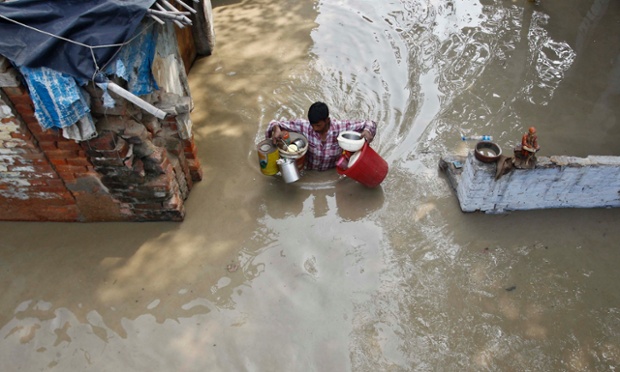 Một người đàn ông mang theo đồ dùng trong khi lội trên đường ngập nước ở New Delhi, Ấn Độ.