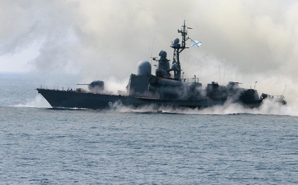 Một tàu hộ vệ tên lửa nhả khói để chống lại một cuộc tấn công trên không, trong khi xả súng vào các mục tiêu trên mặt biển.