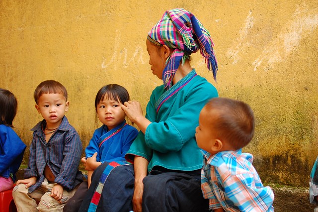 Một người mẹ trẻ đang tranh thủ sửa lại mái tóc cho cô con gái trong khi chờ tới lượt vào khám nha.