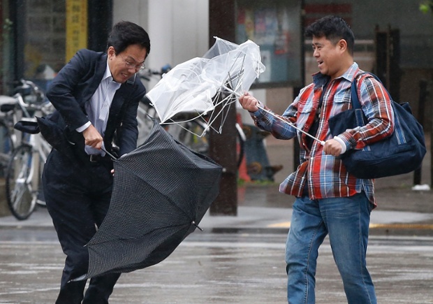 Những người đàn ông vất vã chống chọi với mưa và gió lớn do cơn bão Wipha gây ra tại Tokyo, Nhật Bản.