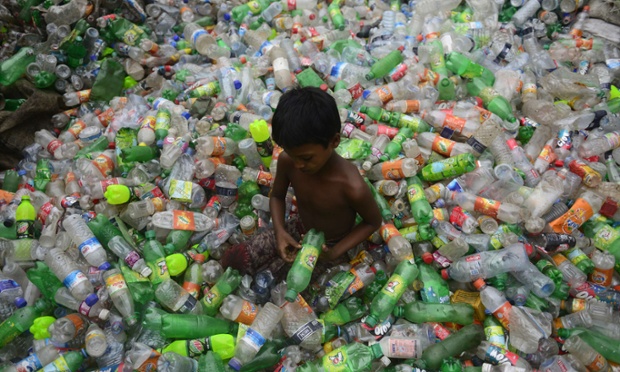 Một cậu bé ngồi phân loại vỏ chai nhựa trong một nhà máy tái chế ở Dhaka, Bangladesh.