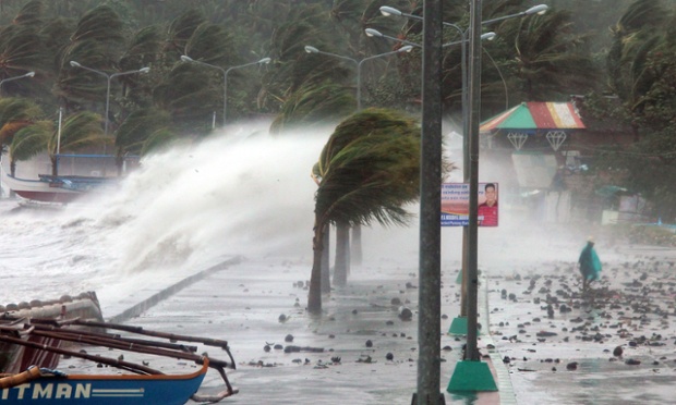 Một người dân đi qua bờ biển với gió mạnh và sóng lớn do siêu bão Haiyan  gây ra tại thành phố Legaspi, Philippines.