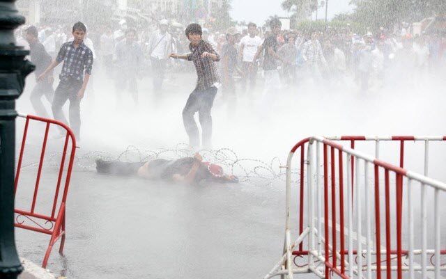 Người biểu tình bị phun vòi rồng trong khi cố dỡ bỏ hàng rào dây thép gai trước Cung điện Hoàng gia ở thủ đô Phnom Penh, Campuchia.