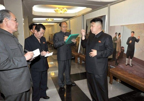 Cả ba quan chức của Trung tâm triển lãm nghệ thuật Mansudae vây quanh Kim Jong Un đều đang bận rộn ghi lại lời ông
