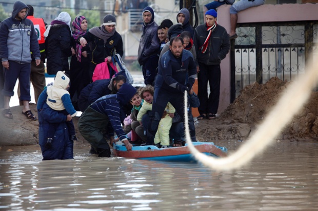 Các nhân viên cứu hộ người Palestine giúp đỡ người dân sơ tán khỏi khu vực bị ngập lụt ở thành phố Gaza.