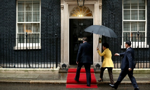 Một thành viên của an ninh Hàn Quốc chạy tới để cầm chiếc ô Tổng thống Park Geun-hye sử dụng để che cho bà và Thủ tướng Anh David Cameron trên đường họ đến số 10 phố Downing.