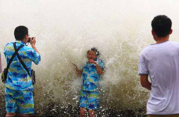 Khách du lịch chụp ảnh với tư thế tựa lưng vào sóng lớn do ảnh hưởng của cơn bão  Wutip tại thành phố Tam Á trên đảo Hải Nam, Trung Quốc.