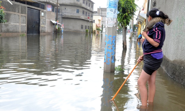 Một phụ nữ mang theo mèo khi đi trên đường phố ngập lụt ở Ciudad Neza, Mexico.