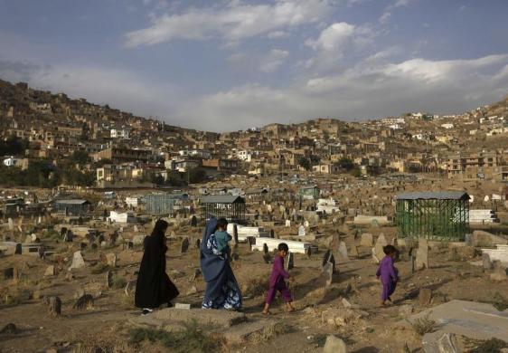 Một gia đình đi qua một nghĩa trang ở thủ đô Kabul, Afghanistan.
