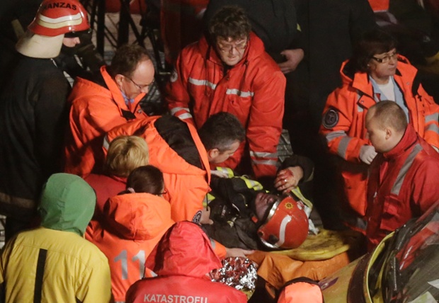 Các nhân viên y tế giúp đỡ một lính cứu hỏa được đưa ra khỏi đống đổ nát của siêu thị Maxima bị sập mái ở Riga, Latvia.
