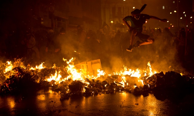 Một người biểu tình nhảy qua hàng rào lửa tại quảng trường Cinelandia ở Rio de Janeiro, Brazil.