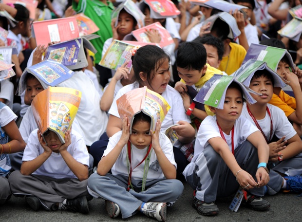 Học sinh của trường Tiểu học Corazon Aquino dùng sách che đầu trong khi diễn tập chống động đất ở Manila, Philippines.