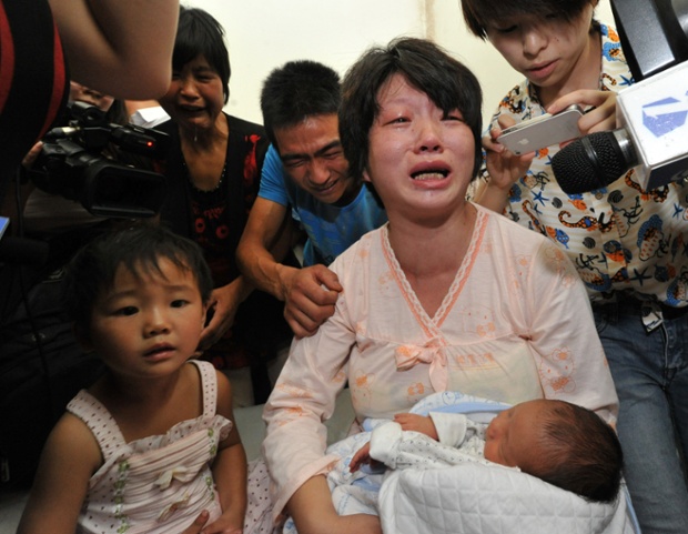Một phụ nữ trẻ tuổi khóc vì sung sướng khi nhận lại đứa con bị y tá bán cho những kẻ buôn bán người tại tỉnh Phú Bình, tỉnh Thiểm Tây, Trung Quốc.