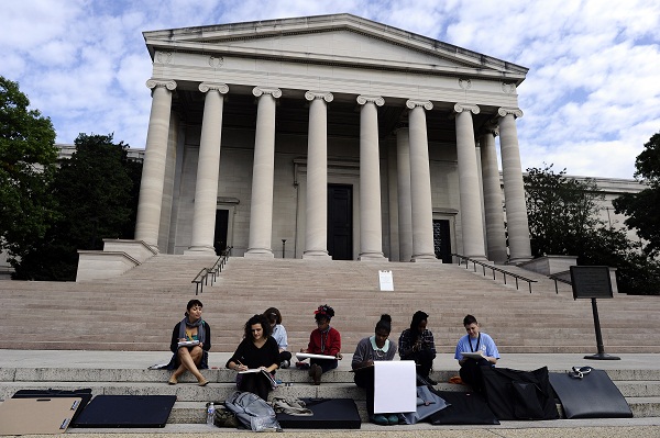 	Một nhóm sinh viên Mỹ ngồi vẽ ở trước cửa Triển lãm nghệ thuật Quốc gia đã bị đóng cửa.
