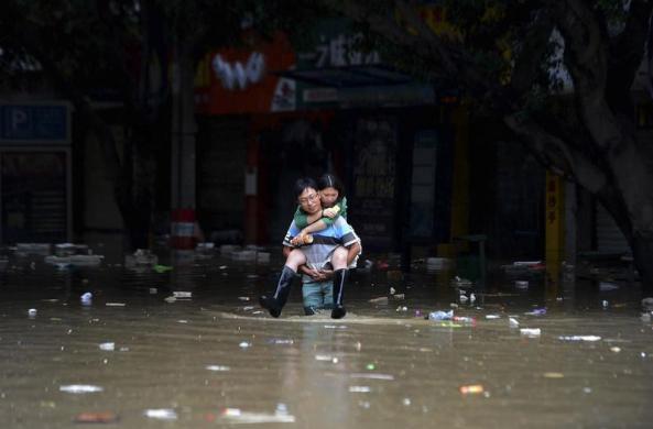 Một người đàn ông cõng một người phụ nữ đi trên đường phố ngập lụt ở huyện Kim Đường thuộc thành phố Thành Đô, Trung Quốc.