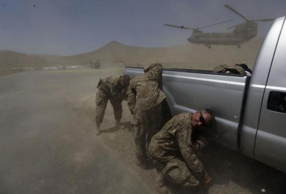 Các bị sĩ NATO nấp sau ô tô để tránh bụi cát khi một chiếc trực thăng hạ cánh tại khu vực ngoại ô Kabul, Afghanistan.