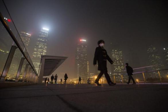 Một người đàn ông phải đeo khẩu trang trên cây cầu dưới trời tối đầy sương mù tại khu Phố Đông, Thượng Hải, Trung Quốc.