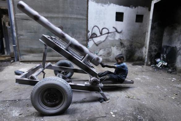 Một cậu bé sửa chữa bệ phóng đạn cối tại nhà máy vũ khí của lực lượng quân đội Syria tự do ở thành phố Aleppo.